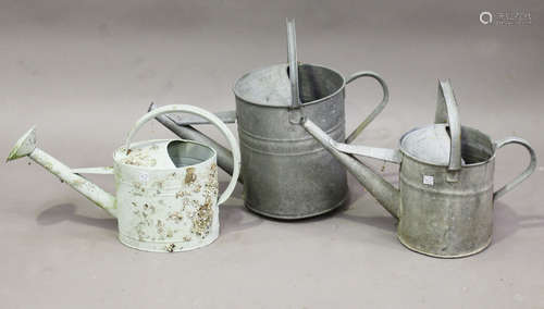 A group of five galvanized watering cans, another watering can, a galvanized two-handled tub and