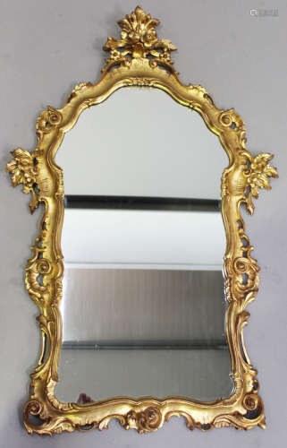 A late 20th century giltwood wall mirror with a carved floral frame, 110cm x 67cm (chip to frame).