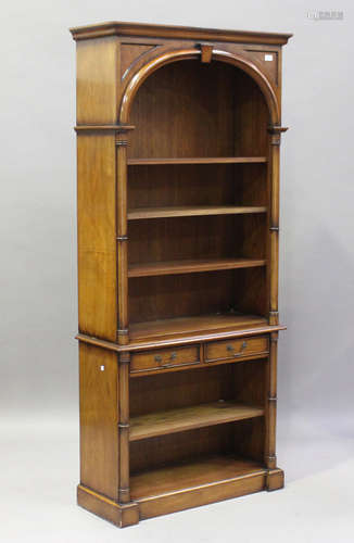 A 20th century reproduction walnut open bookcase with arched recess and two oak-lined drawers,