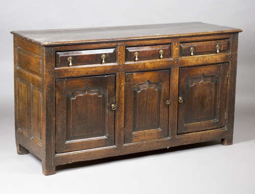A mid-18th century provincial oak dresser base, fitted with three drawers above arched panel