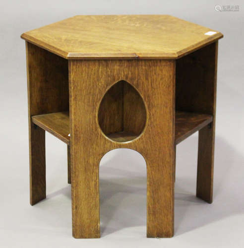 An early 20th century Arts and Crafts oak hexagonal book table, three sides pierced with teardrop