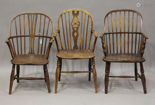 A group of three mid-19th century ash and elm Windsor armchairs, all raised on turned legs,