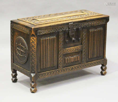 An early 20th century Arts and Crafts style carved walnut coffer, the hinged lid and front with a