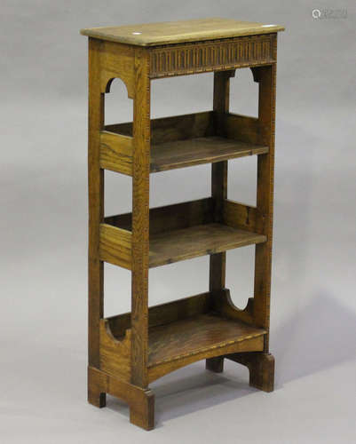 An early 20th century Arts and Crafts style oak open bookcase with a stop-fluted frieze and arched