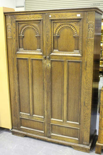 A mid-20th century Jacobean Revival oak bedroom suite by Lock of London, comprising two wardrobes, a