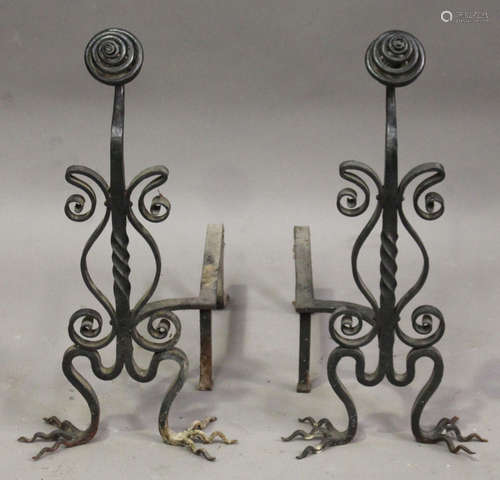 A pair of early 20th century Arts and Crafts wrought iron fire andirons, each spiral ovoid finial