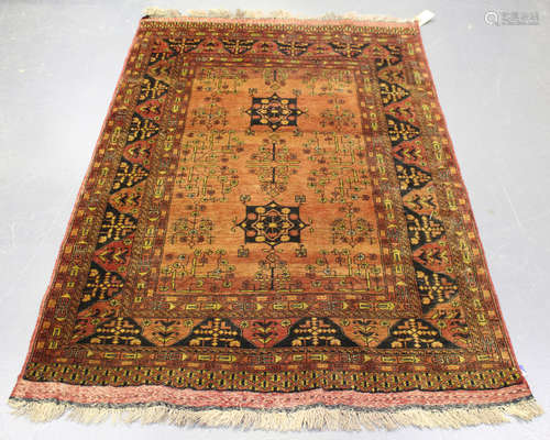 An Afghan rug, mid/late 20th century, the shaded chestnut field with angular medallions and floral