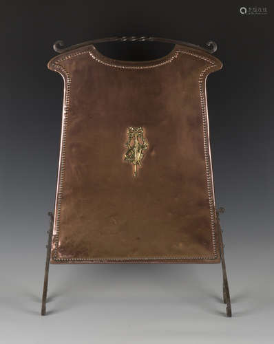 An early 20th century Arts and Crafts copper firescreen with a central applied brass motif and steel