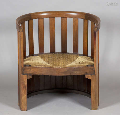 An Edwardian Arts and Crafts mahogany barrel back chair by Liberty & Co, the curved upright comb