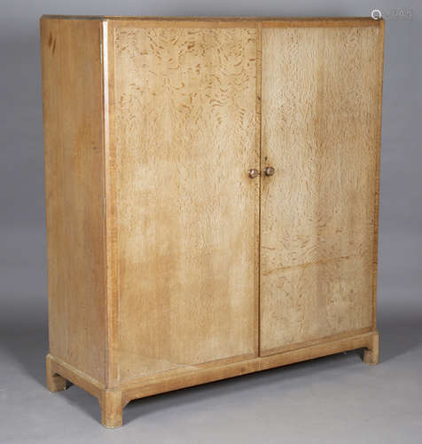 An early 20th century limed oak compactum wardrobe, in the manner of Heals, the two doors