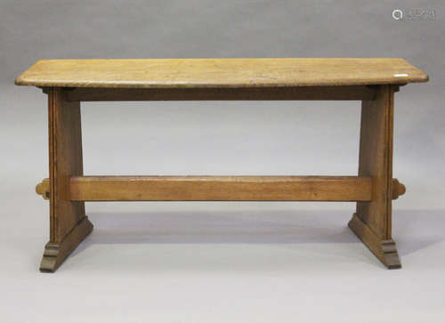 An early 20th century Arts and Crafts oak window seat, the shaped top raised on reeded plank