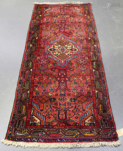 A Hamadan runner, North-west Persia, mid-20th century, the shaded red field with a shaped medallion,