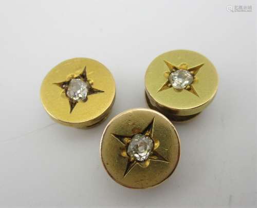 Three gold coloured metal dress studs, each set with a diamond