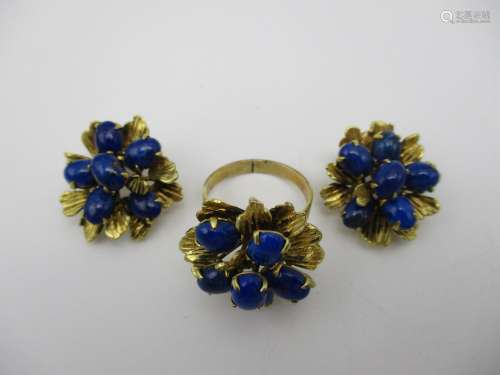 A gold ring fashioned as a flower with textured leaves, set with blue cabochons and a pair of