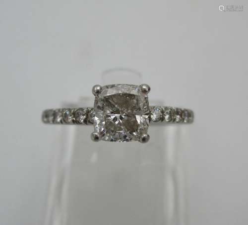 A platinum coloured diamond ring set with a single cushion diamond, measuring 5.7mm x 5.9mm,