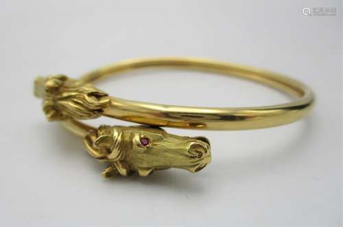 A Cartier style French gold double equestrian bangle, modelled with two horse heads inset with