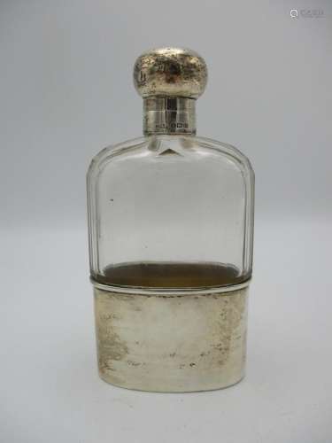 A George V silver mounted glass hip flask, with engine turned detail to the lid, glass body with