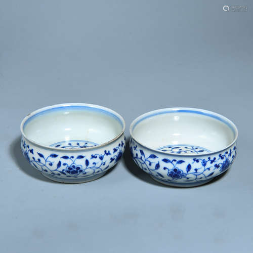 A PAIR OF CUPS PATTERNED WITH WHITE AND BLUE FLOWERS TWINING ROUND BRANCHES