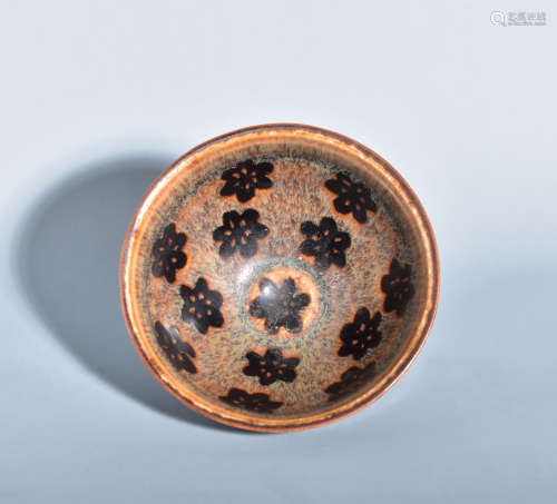 A BLACK GLAZED TEA CUP PATTERNED WITH PLUM