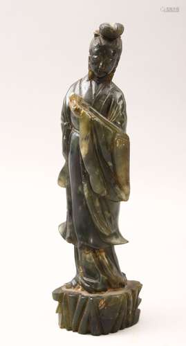 A 20TH CENTURY CHINESE CARVED JADE FIGURE OF GUANYIN, stood upon a stylized stump base holding a