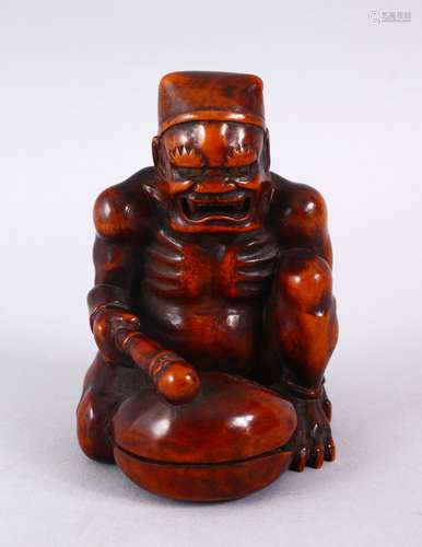 A GOOD JAPANESE MEIJI PERIOD CARVED WOODEN OKIMONO OF AN ONI BEATING A MOKUGYO, in a seated position