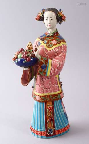 A CHINESE FAMILLE ROSE POTTERY FIGURE OF A LADY HOLDING FLORA, the underside with calligraphy and