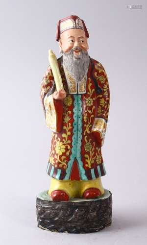 A CHINESE FAMILLE ROSE POTTERY FIGURE OF A SCHOLAR, holding a scroll upon a stylized base, 22cm