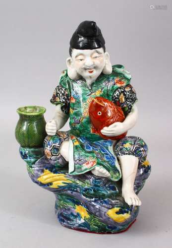 A GOOD JAPANESE MEIJI PERIOD KUTANI PORCELAIN FIGURE OF A GOD SEATED UPON A ROCK, holding his fish