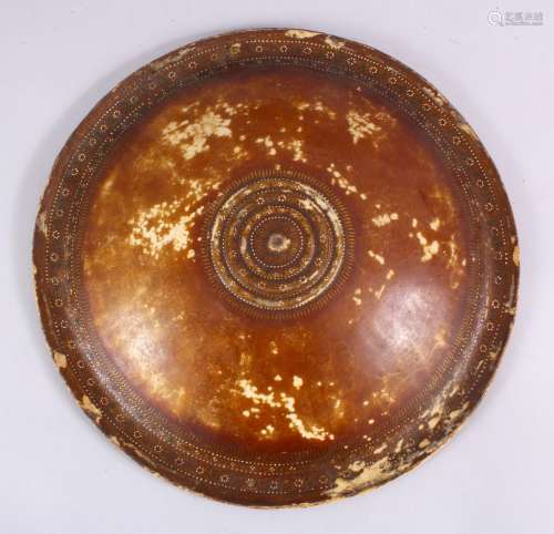 A 19TH CENTURY INDIAN LEATHER SHIELD, 34cm diameter.