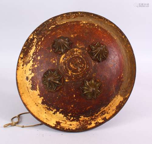 A 19TH CENTURY INDIAN PAINTED LEATHER SHIELD WITH BRASS BOSSES, with traces of gilding, 32cm.