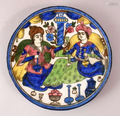 A PERSIAN QAJAR GLAZED POTTERY DISH of two figures seated, 24cm