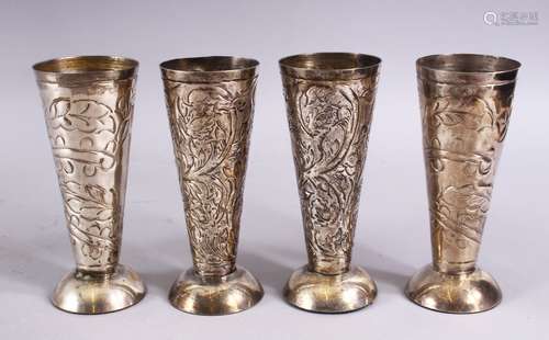 FOUR 19TH CENTURY ISLAMIC WHITE METAL CARVED BEAKERS, carved with floral design, 14.5cm.