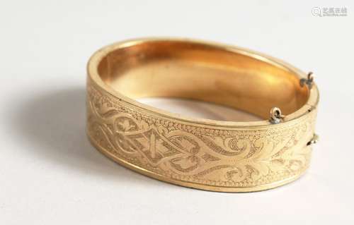 AN ENGRAVED GILT METAL BANGLE.