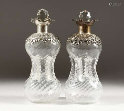 A PAIR OF HOURGLASS DECANTERS, with embossed silver rims and collars, London 1900. 8.5ins high.