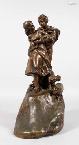 A LATE 19TH CENTURY BRONZE GROUP OF YOUNG LOVERS in an embrace, standing on a hill with sheep at