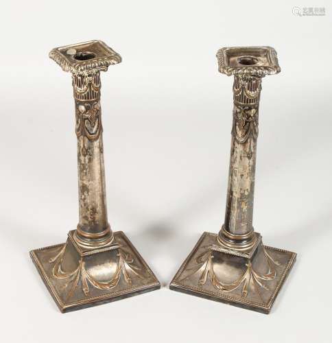 A PAIR OF ADAM DESIGN PLATE CANDLESTICKS with swags. 11ins high.