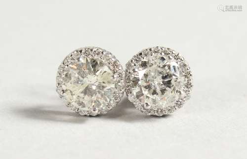 A PAIR OF DIAMOND EAR STUDS, the central stone surrounded by further small diamonds.