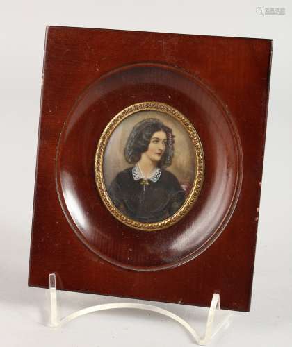 AN OVAL PORTRAIT MINIATURE OF A YOUNG LADY in a wooden frame. 2.25ins x 2ins. Signed.