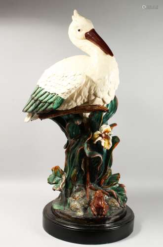 A LARGE MAJOLICA STORK STICK STAND, standing beside an open flower, on a circular base. 40ins high.