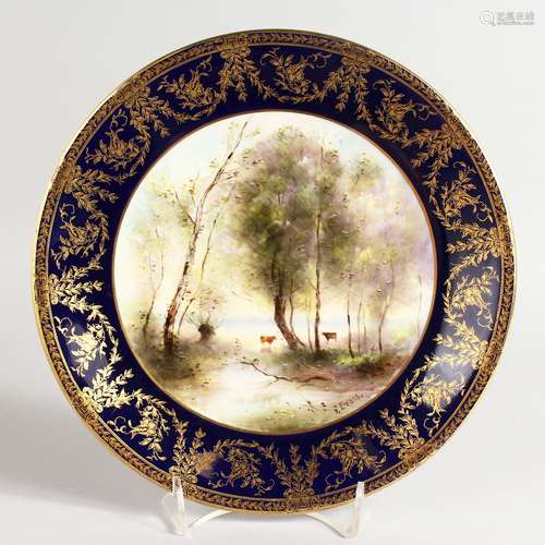 A ROYAL WORCESTER PLATE painted with cattle beside a lake beneath a blue and gilt border by George