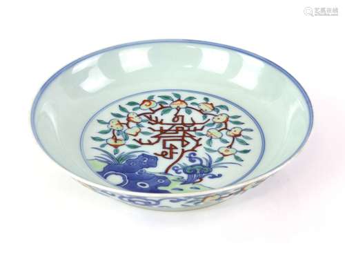 A doucai style dish decorated with flowering peaches and rockwork; the base with Qianlong six-