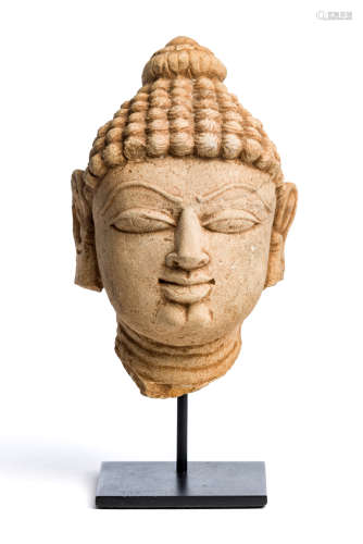 A BUFF SANDSTONE HEAD OF A JINA, WESTERN INDIA, 11TH/12TH CENTURY