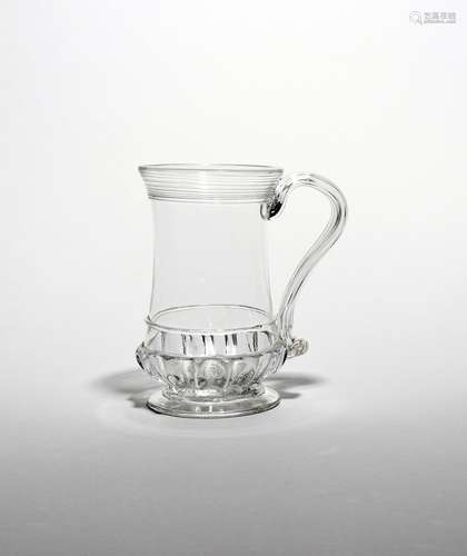 A glass tankard c.1780, the slightly waisted form with a band of gadrooning above the circular foot,