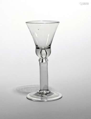 A wine glass c.1740, the base of the bell bowl enclosing a large tear, raised on a thick plain