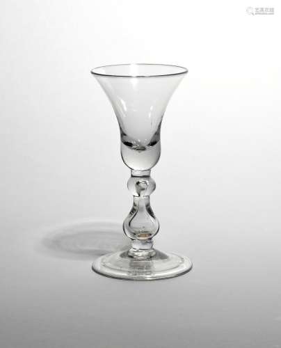 A heavy baluster glass c.1710, with a generous bell bowl raised on a baluster stem with cushion knop