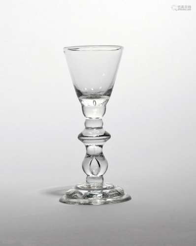 A rare baluster wine glass c.1725, with rounded funnel bowl raised on a baluster stem with half knop