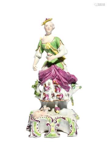 A Derby figure of a shepherdess c.1757, standing on a tall scrolled base, a lamb recumbent at her