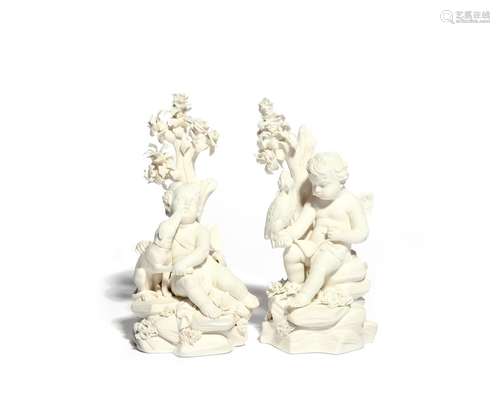 A pair of Derby biscuit porcelain figures of putti c.1780, each seated on rockwork beneath an oak