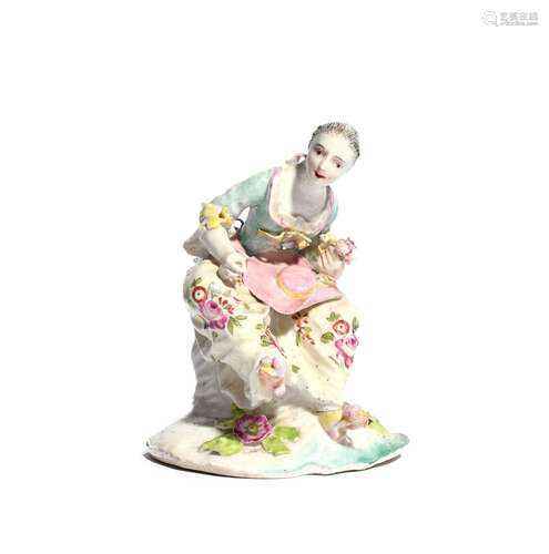 A Derby dry-edge figure of a girl c.1755, seated with her right foot raised and leaning over a large