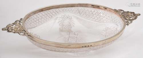 A VICTORIAN OVAL SILVER MOUNTED CUT GLASS BOWL, WITH CAST OPENWORK CHERUBS AND MASK HANDLES, 29CM